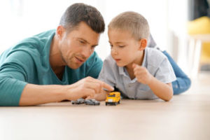 Man and boy playing with die-cast cars